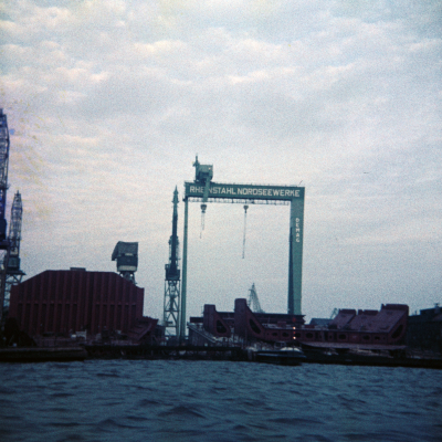 Farbfoto von der Werft RHEINSTAHL NORDSEE WERKE in Emden an einem Abend im Jahr 1967. Aufgenommen vom Hafenrundfahrtsboot aus.