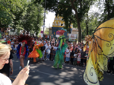 Farbfoto von Menschen, die auf Stelzen gehen auf dem Umzug vom Karneval der Kulturen auf der Straße Hasenheide in Berlin am 28. Mai 2023. Fotograf: Erwin Thomasius.