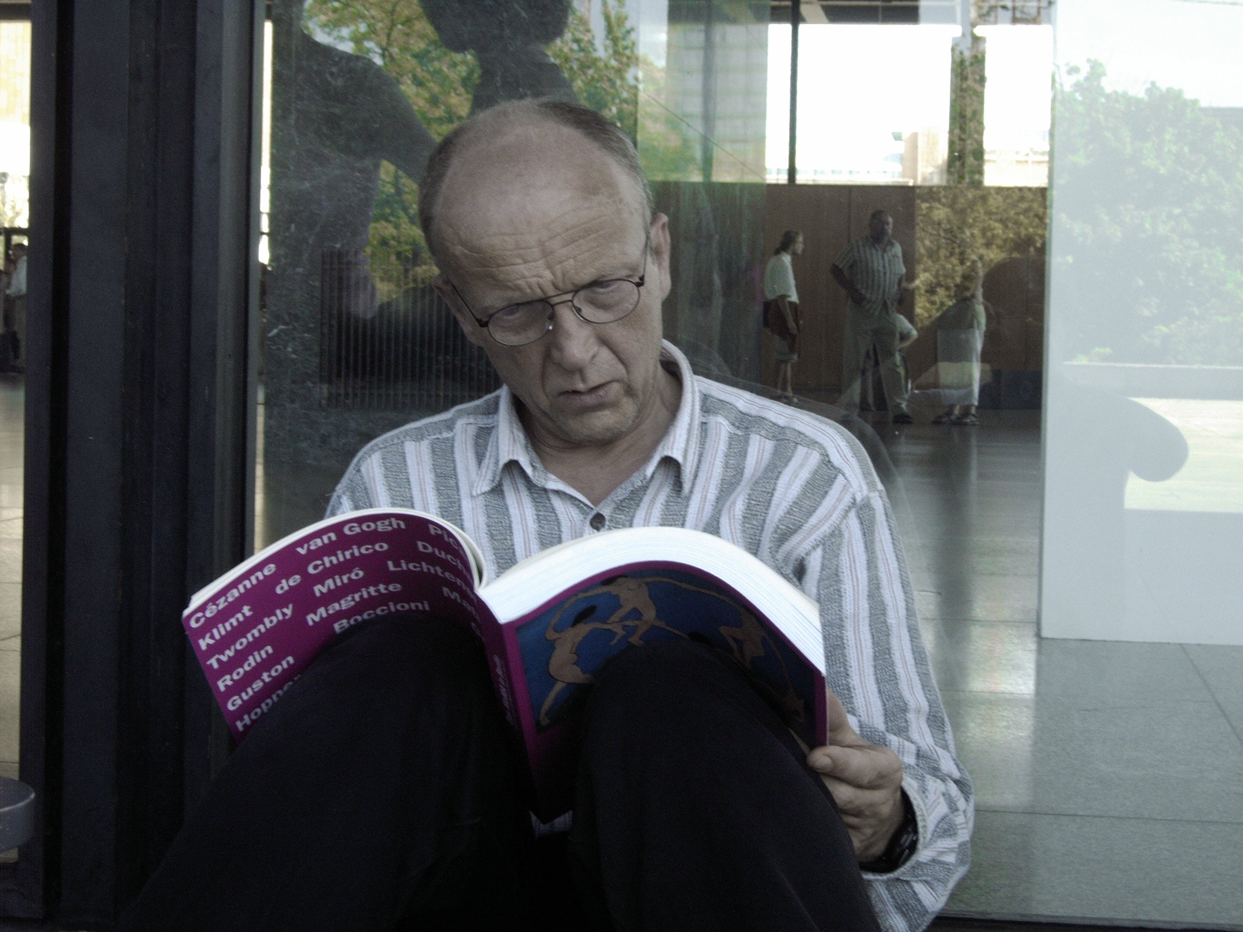 In der Schange um die Neue Nationalgalerie in Berlin waehrend der Kunstausstellung Das MoMA in Berlin lese und betrachte ich den Ausstellungskatalog. September 2004. Photo: Kim Hartley.