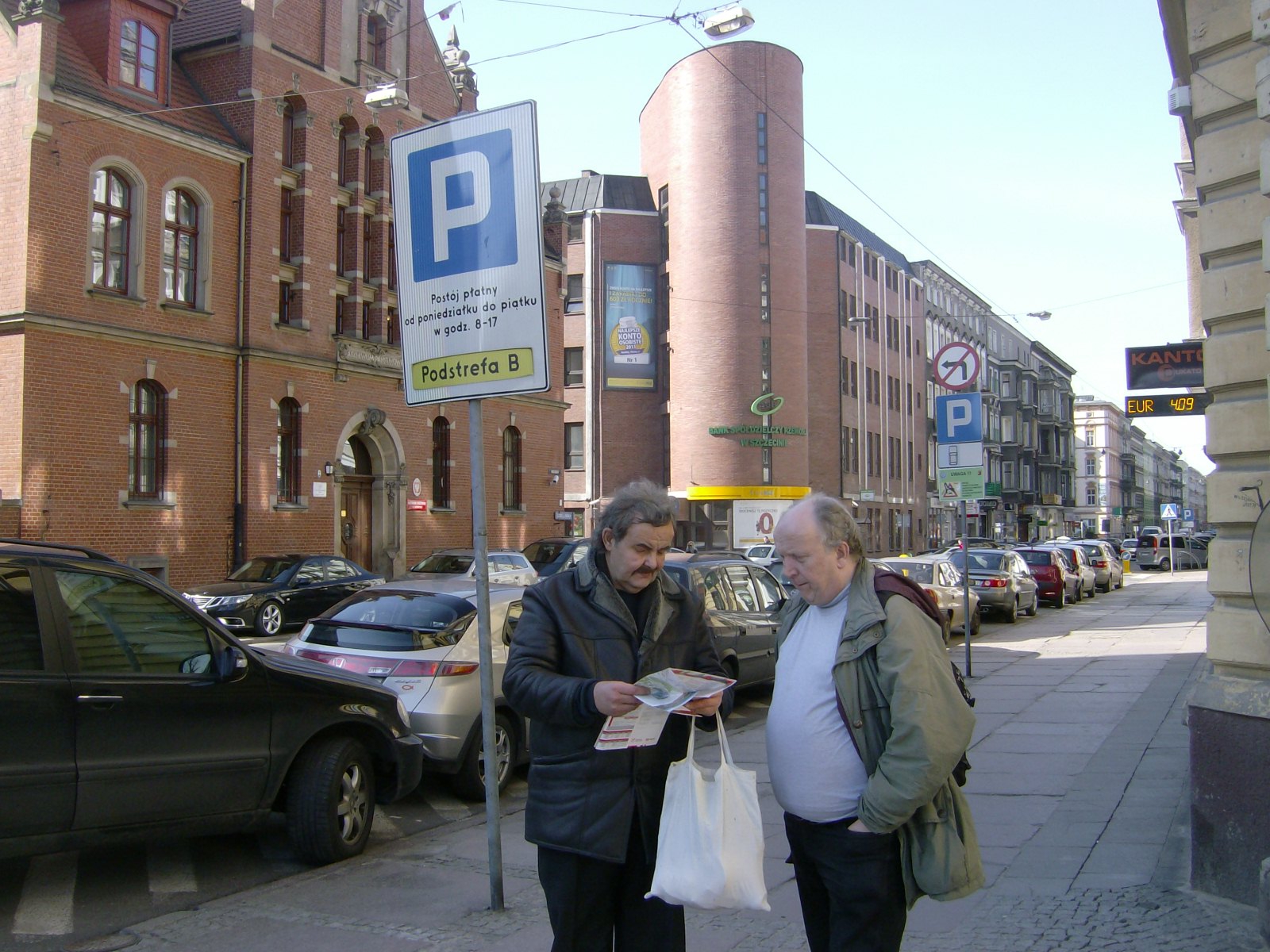 Farbfoto: ... und Erwin Thomasius in Stettin bei der Suche nach dem richtigen Weg. Rechts im Bild ein Kantor mit dem aktuellen Wechselkurs des Euro zum Polnischen Zloty. Fotograf: R.I.